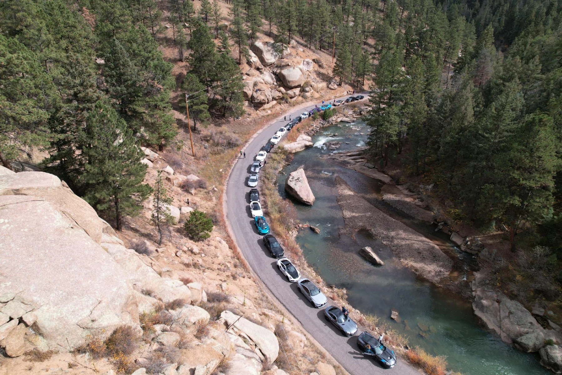 A line of cars beside a forested river